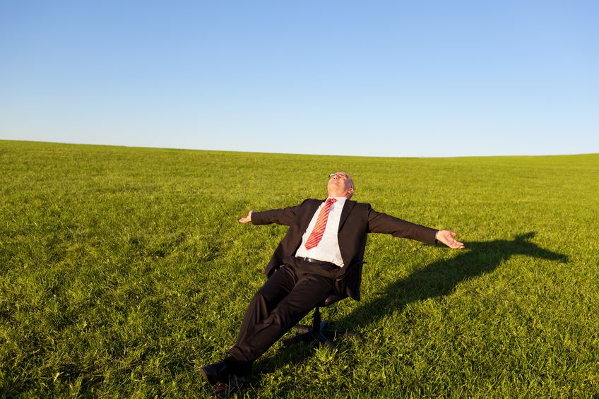 Businessman Falling into Field of Green Grass with Arms Oustretched